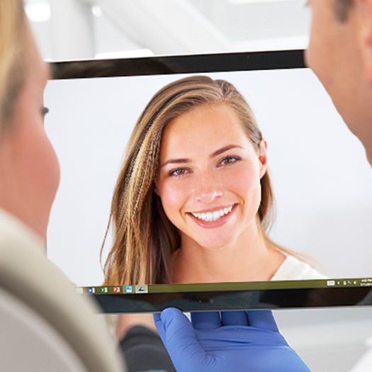 Dentist and patient looking at virtual smile design on computer screen