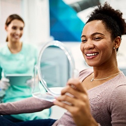 Woman smiling at reflection in dentist's mirror