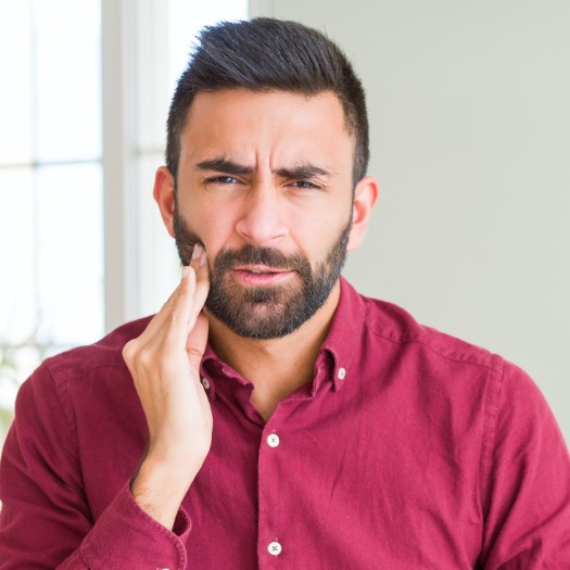 Man in need of emergency dentistry holding his jaw