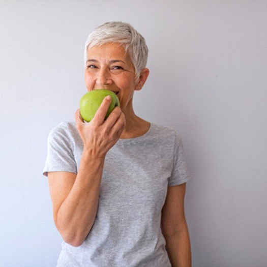 Happy older woman biting into an apple