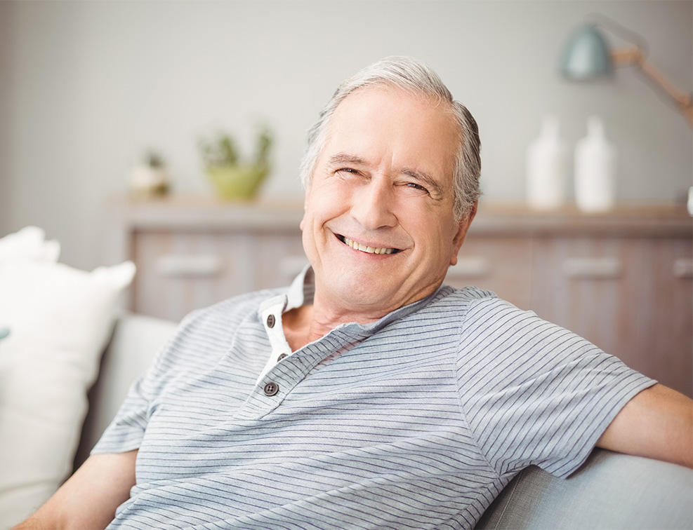 Senior man leaning back on couch and smiling