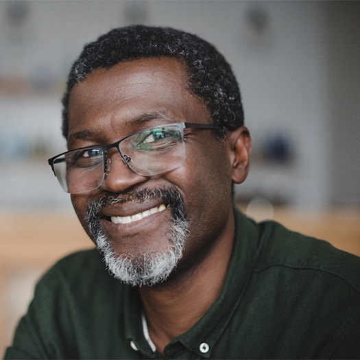 Senior man with glasses smiling in kitchen