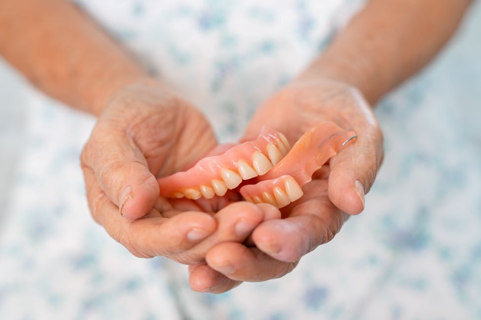 A closeup of hands holding a pair of dentures