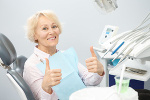 Senior woman giving two thumbs up at the dentist